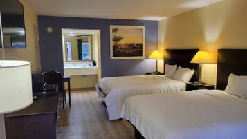 Une chambre d’hôtel avec deux lits, un bureau, une chaise, un miroir et un tableau au mur.