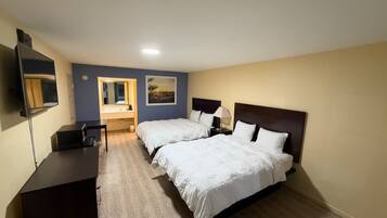 A hotel room with two beds, a desk, a TV, and a painting on the wall.