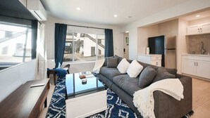 A modern living room with a sofa, coffee table, and a view of a building outside.