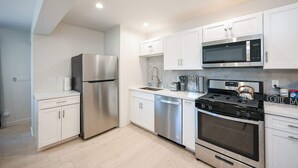 A modern kitchen with white cabinets, stainless steel appliances, and a gas stove.