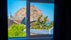 A view of a mountain from a window, with a building and greenery in the foreground.