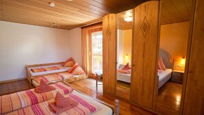 Une chambre avec trois lits, un plancher en bois et un grand miroir.