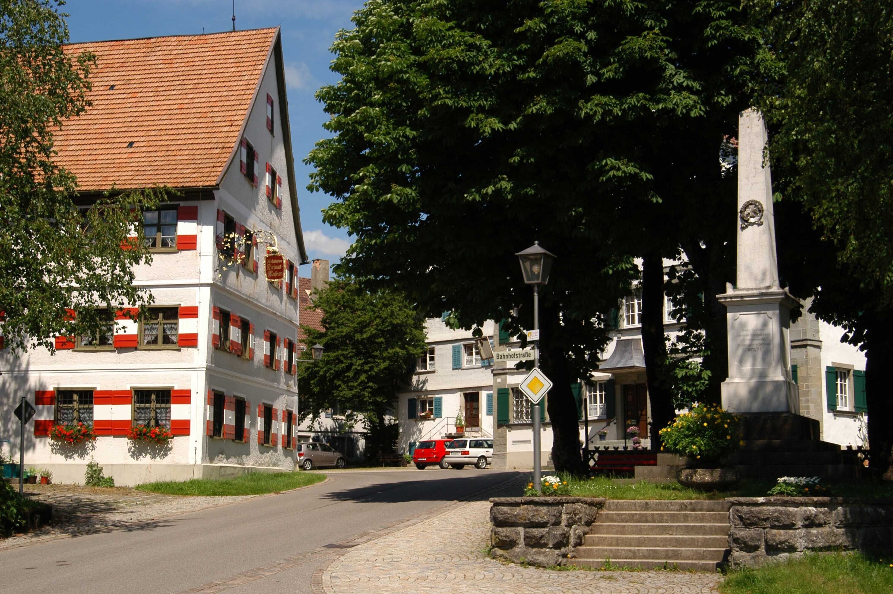 A traditional European building with a tiled roof, a statue, and a street with cars.