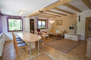A dining area with a wooden table and chairs, a sofa, and a cabinet.