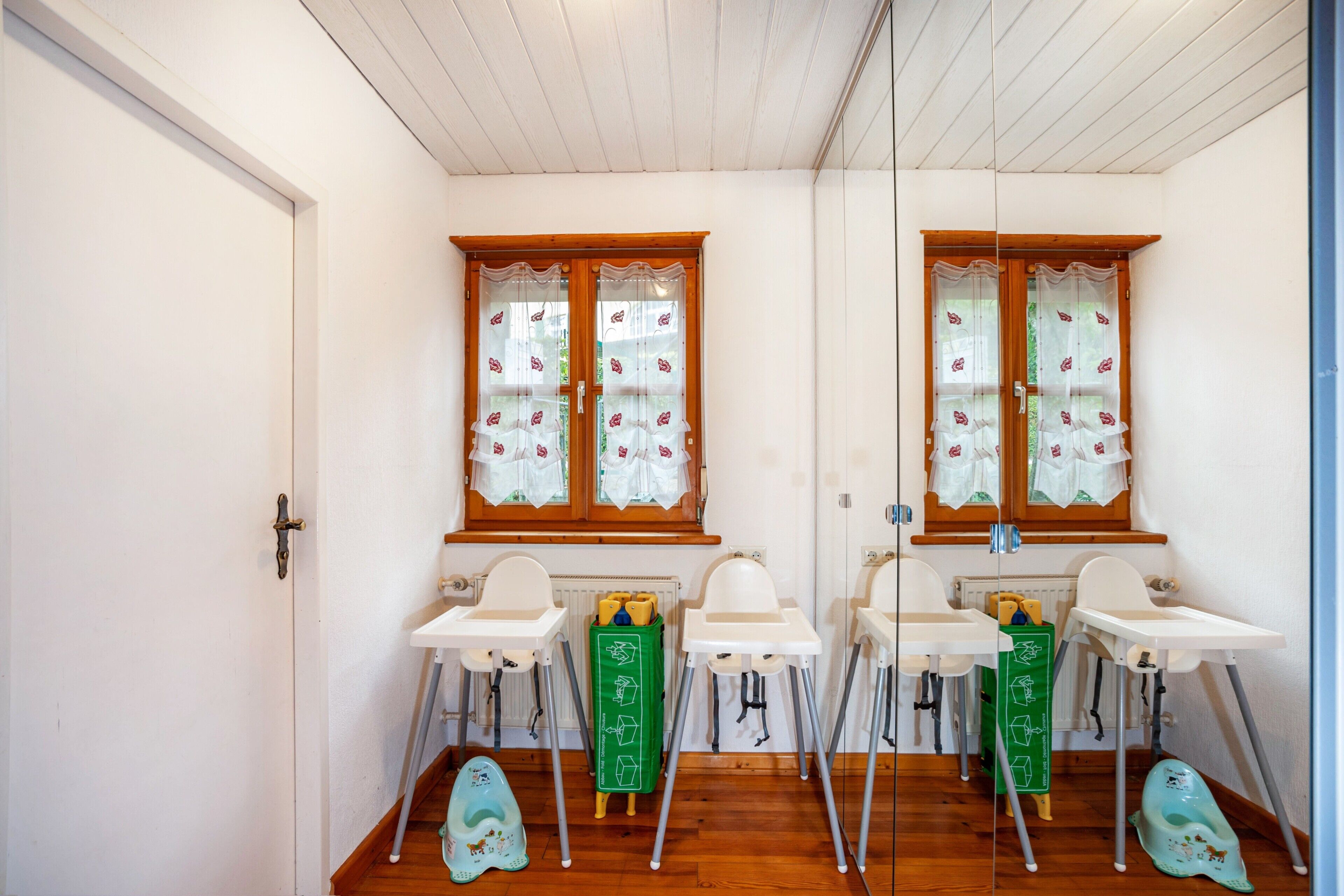 Een kinderkamer met twee wastafels, twee verhoog stoelen en een groene opbergkast.