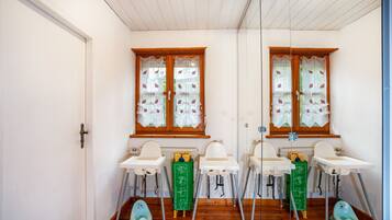 Een kinderkamer met twee wastafels, twee verhoog stoelen en een groene opbergkast.