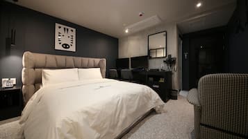 A modern bedroom with a large bed, a desk, and a chair.