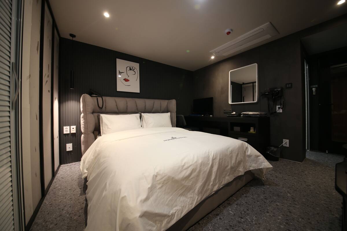 Une chambre à coucher moderne avec un grand lit, un bureau et un miroir.