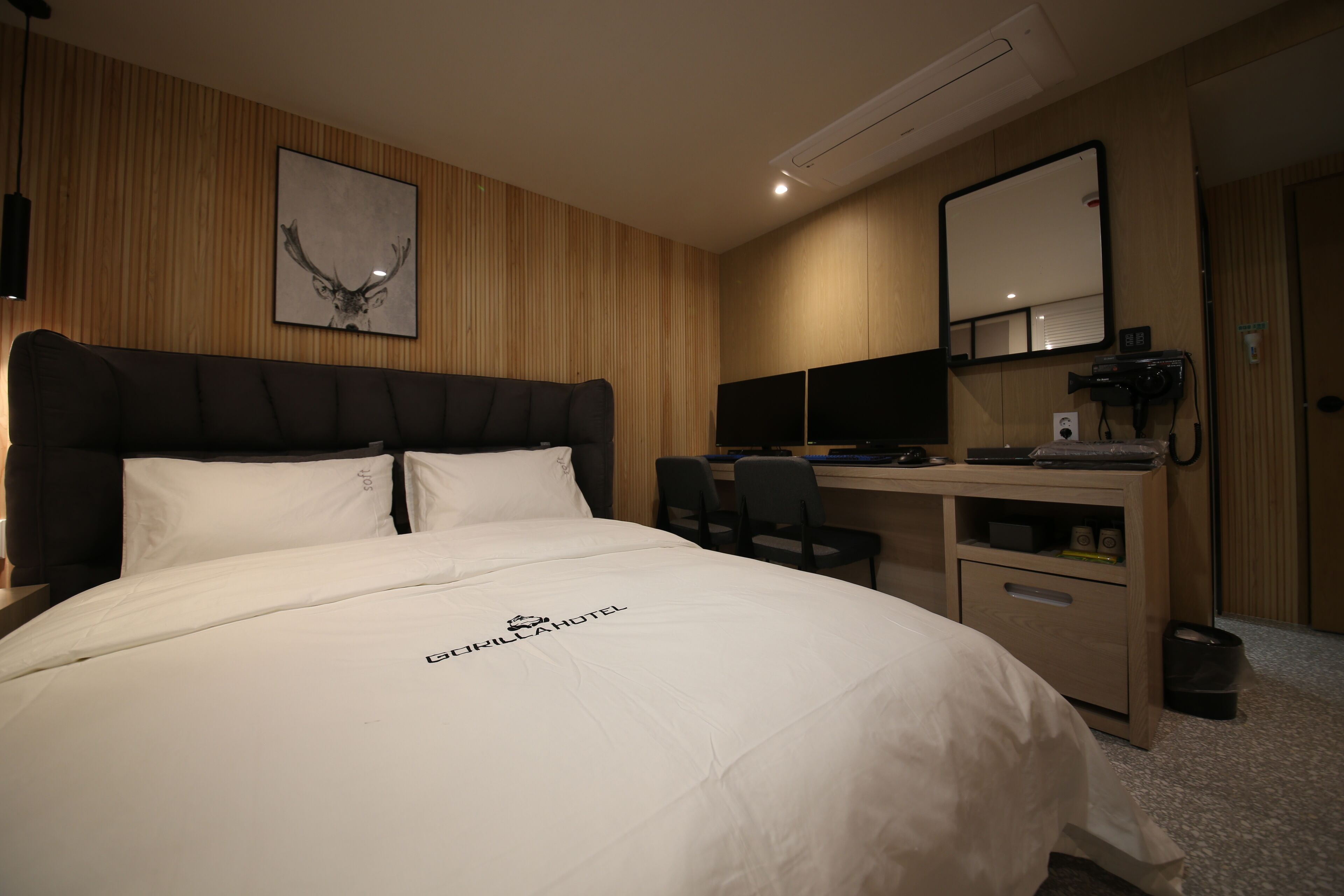 A hotel room with a bed, a desk, a chair, a mirror, and a picture on the wall.