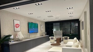 Un espace d’accueil moderne doté d’un téléviseur à écran plat, de sièges et d’une plante.