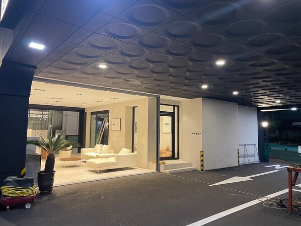 Una entrada de hotel moderna con un mostrador de recepción, una zona de estar con sofás y una planta en maceta.