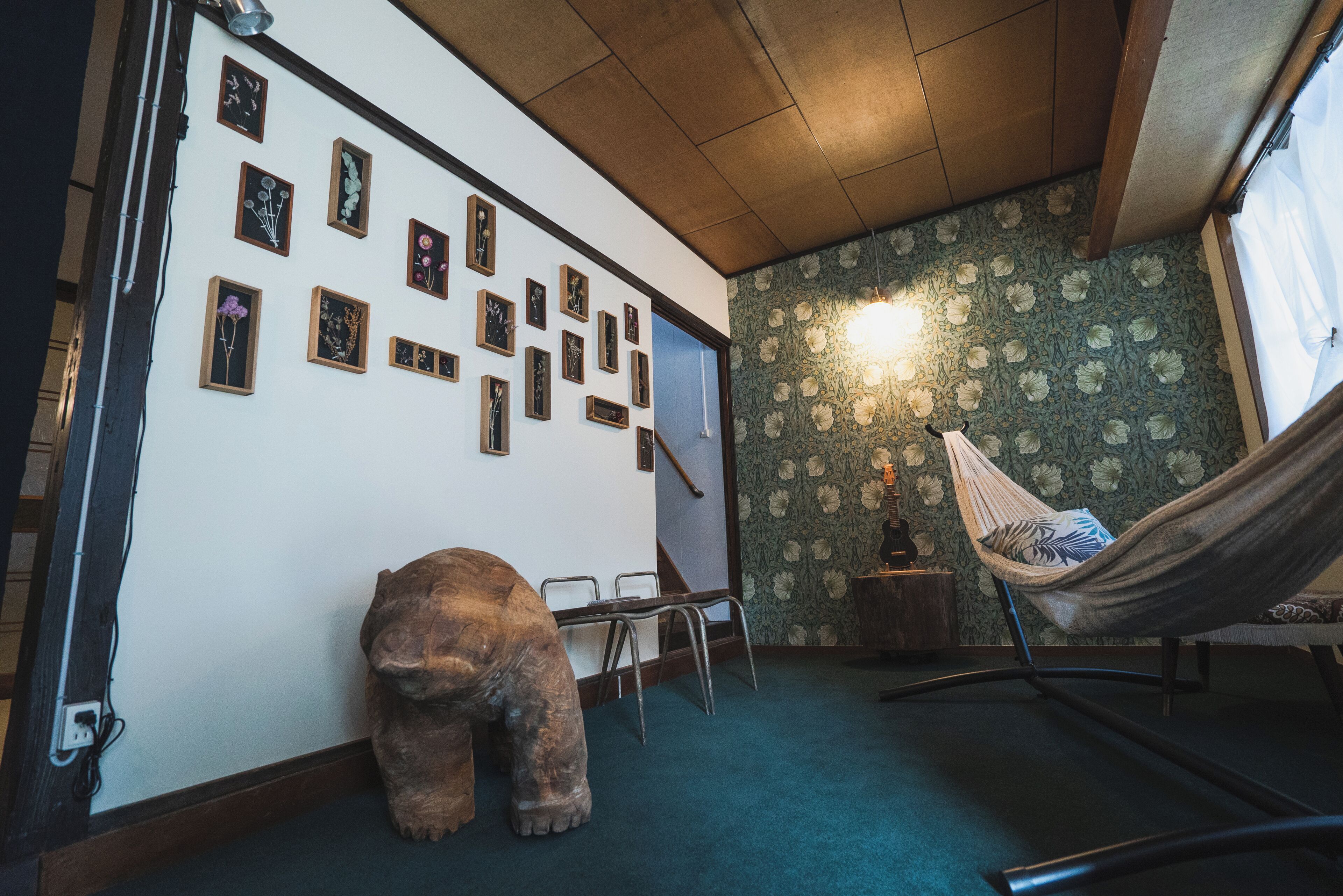 A room with a large bear sculpture, a hammock, and a wall decorated with framed pictures.