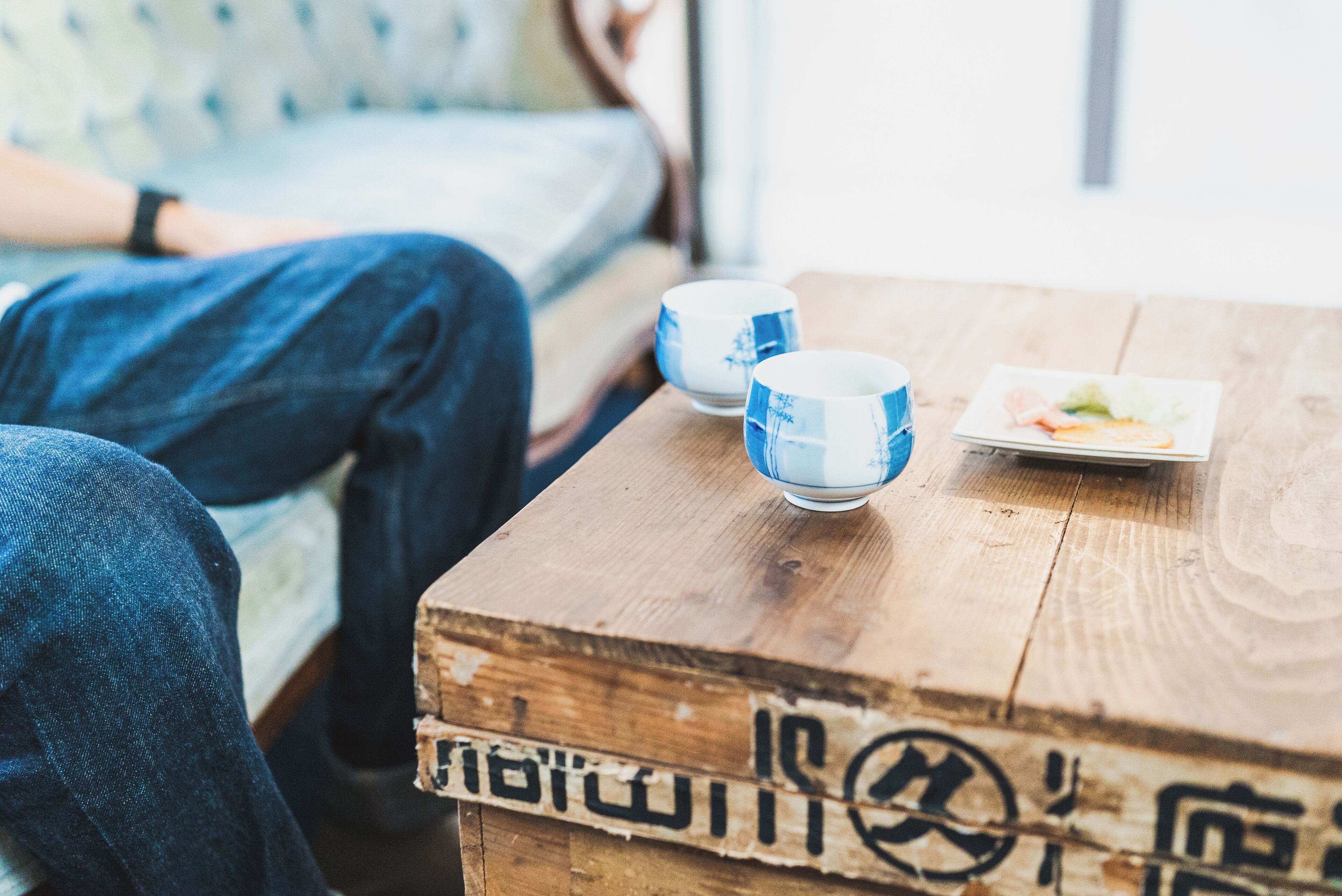 Une table en bois avec deux tasses bleues et blanches et une assiette de nourriture.