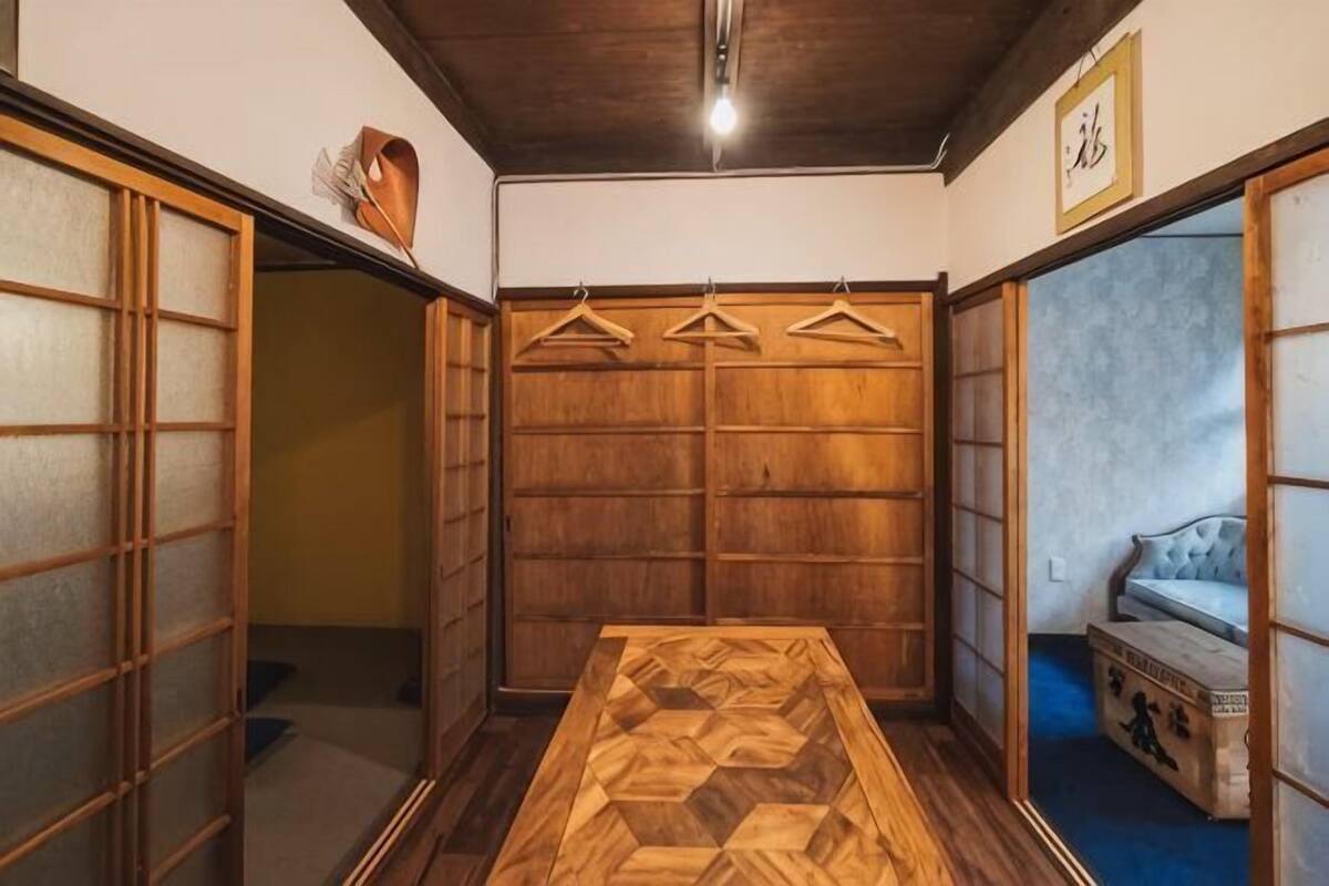 A traditional Japanese room with tatami flooring, a wooden table, sliding doors, and a hanging clothes rack.