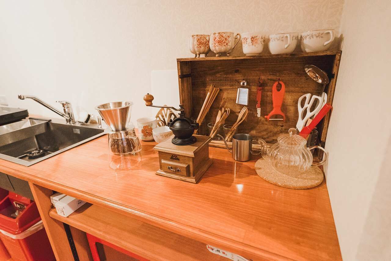 A kitchen counter with a coffee maker, tea kettle, and various utensils.