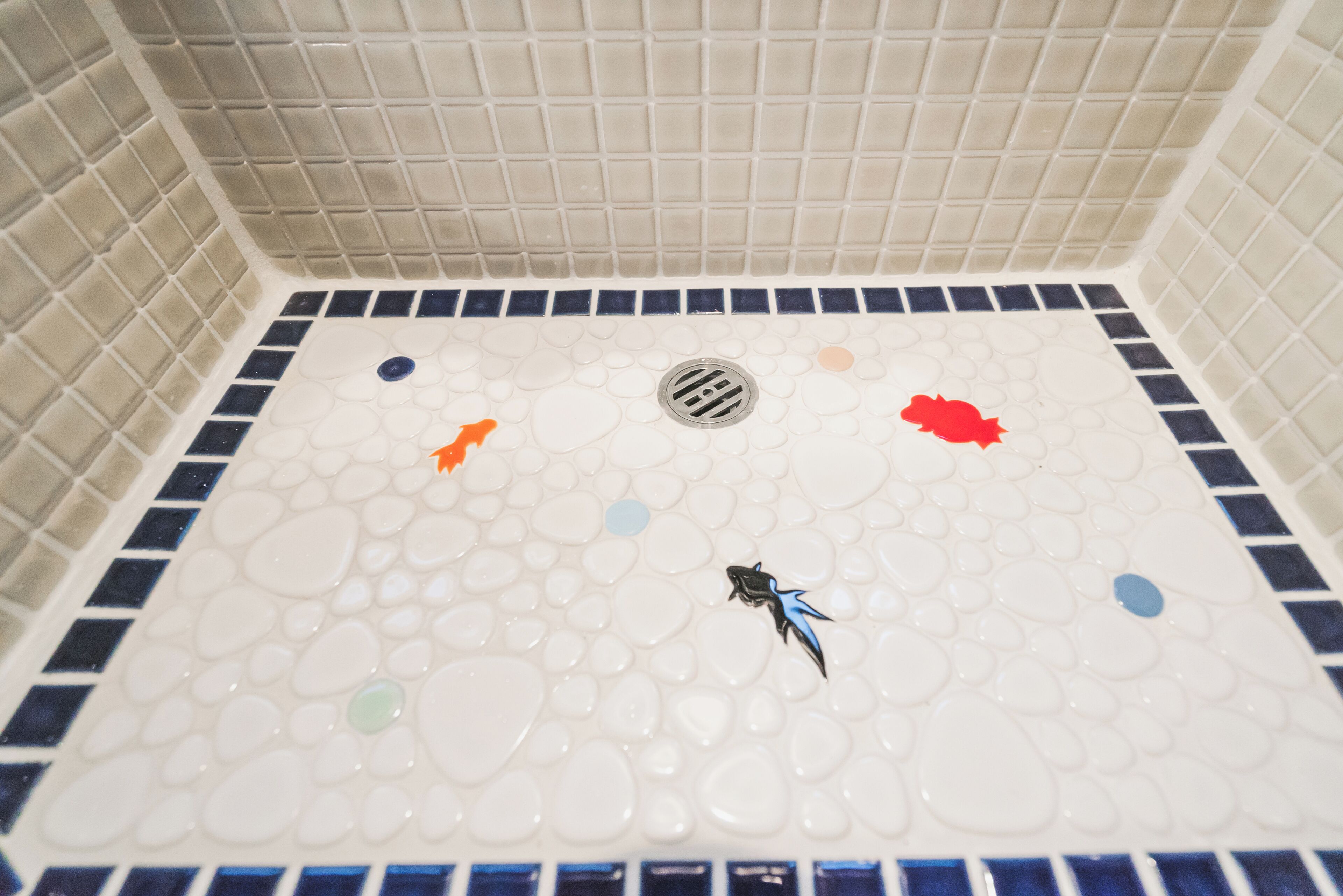 A tiled shower area with a drain in the center, surrounded by decorative tiles.