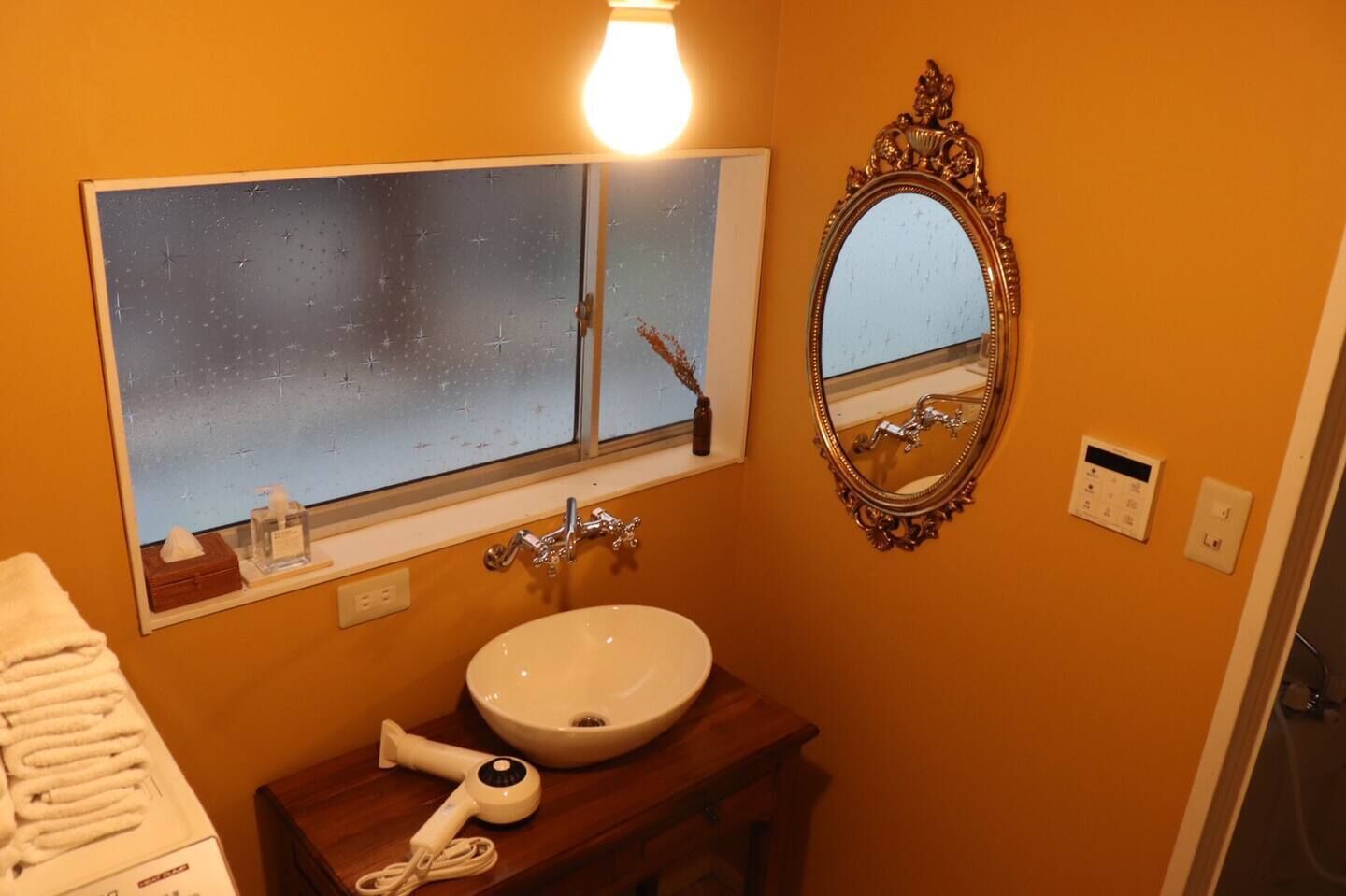 A bathroom with a white sink, a mirror, and a hairdryer on a wooden counter.