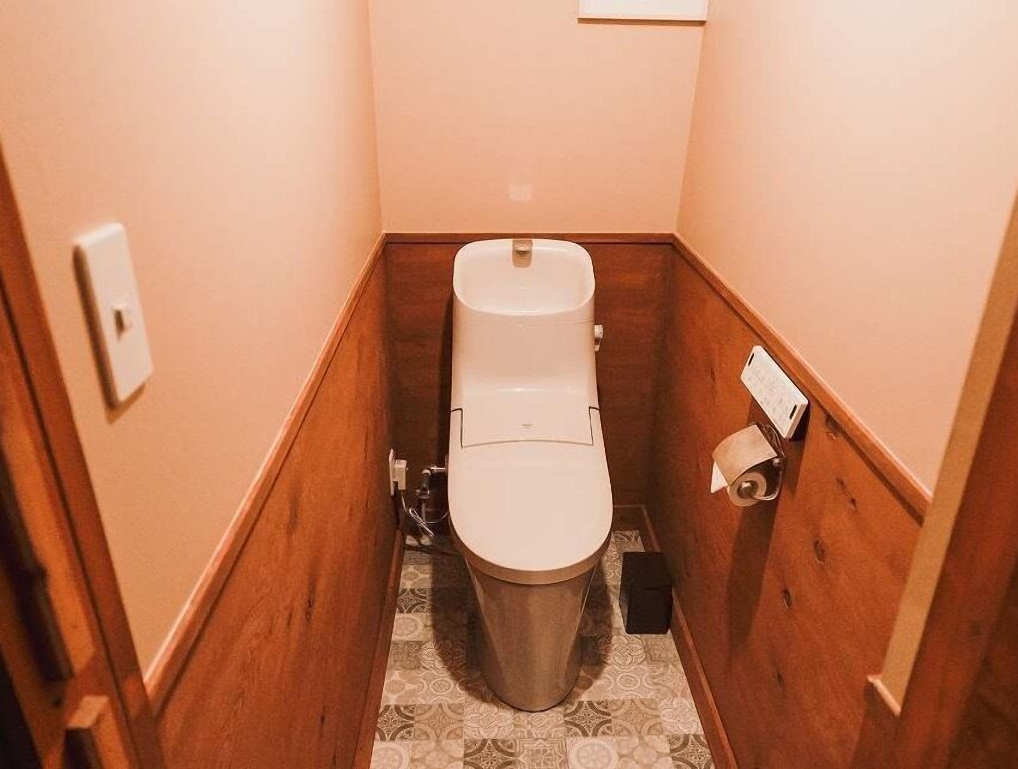 Un bagno stretto con il water, un dispenser di carta e un pavimento decorato.