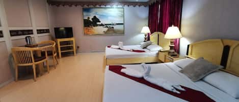 A hotel room with two beds, a desk with a chair, a television, and a painting on the wall.