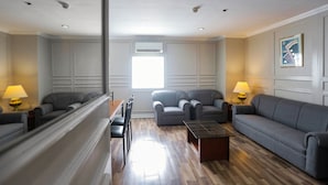 Una sala moderna con sofás grises, una mesa de centro de vidrio y un comedor con sillas.