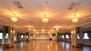 Un amplio salón con suelo de madera, múltiples candelabros y grandes ventanales.