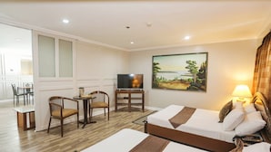 Habitación de hotel con dos camas, televisión, un cuadro y un comedor con sillas y mesa.