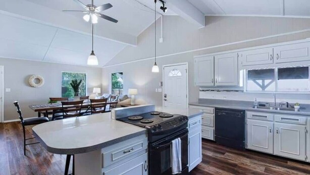 A modern kitchen with white cabinets, a central island, and a dining area with a bench.