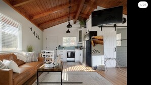 Un salón amplio con un sofá de cuero marrón, una mesa de centro y un televisor montado en la pared.