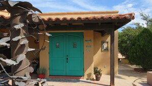 Un bâtiment avec une porte verte, un toit en tuiles et une cour intérieure en pierre.