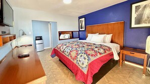 Ein Hotelzimmer mit Bett, Schreibtisch, Stuhl, Fernseher, Mikrowelle und Kühlschrank.