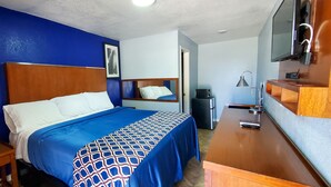 Ein Hotelzimmer mit Bett, Schreibtisch, Fernseher und Mülleimer.