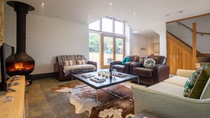 A cozy living room with a stone fireplace, leather sofas, and a glass coffee table. - Spring Barn, Chipping Norton - sleeps 4 guests  in 2 bedrooms (Great Rollright)