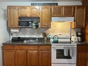 A kitchen with wooden cabinets, a microwave, a stove, a sink, and a toaster.