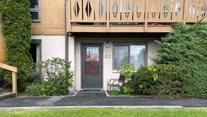 Ein Gebäude mit einem Holzbalkon, einer mit der Nummer 02 gekennzeichneten Tür und einer kleinen Bank davor.