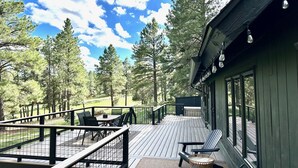 A wooden deck with outdoor seating, surrounded by tall trees and a clear sky. - Flagstaff Bogey Inn! A-Frame cabin Golf Course Lot (Flagstaff)