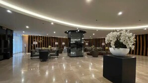 Eine geräumige Lobby mit poliertem Boden, einer Sitzgelegenheit und einer zentralen Zierensäule.