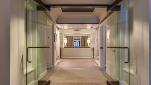 A modern hotel corridor with glass doors, a central light fixture, and a view into a room with a window and a door at the end. - The Woods Resort and Spa Killington: 2 BR / 2 BA Renovated Condos w/ Great Amenities V7 (Killington)
