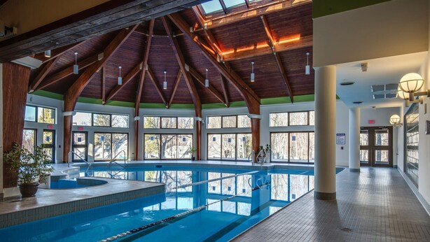 An indoor swimming pool with a high ceiling and large windows. - The Woods Resort and Spa Killington: 2 BR / 2 BA Renovated Condos w/ Great Amenities V7 (Killington)