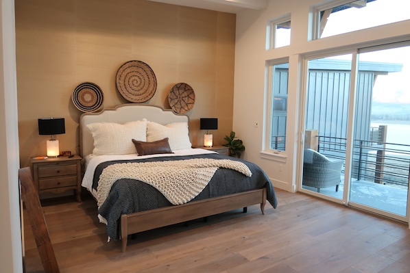 Un dormitorio con una cama grande, dos mesitas de noche con lámparas y vistas a un balcón.