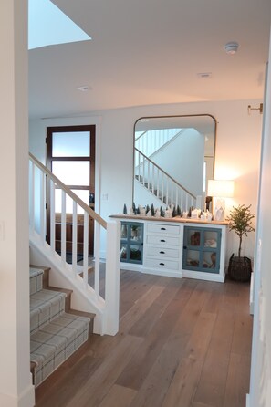 Staircase leads to an upper level, with a cabinet and mirror adding to the clean, minimalist design.