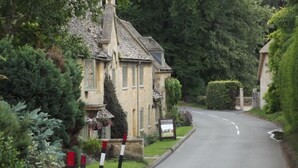 Ein charmantes Steinhaus mit traditionellem Design, eine gewundene Straße und ein Schild.