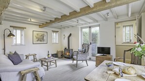 Ein gemütliches Wohnzimmer mit Kamin, einer Couch, einem Esstisch mit Tellern und Brot sowie einem Fernseher.