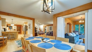 Un vaste espace dédié à la salle à manger, avec une grande table en bois et des sets de table bleus, entourée de chaises en bois.