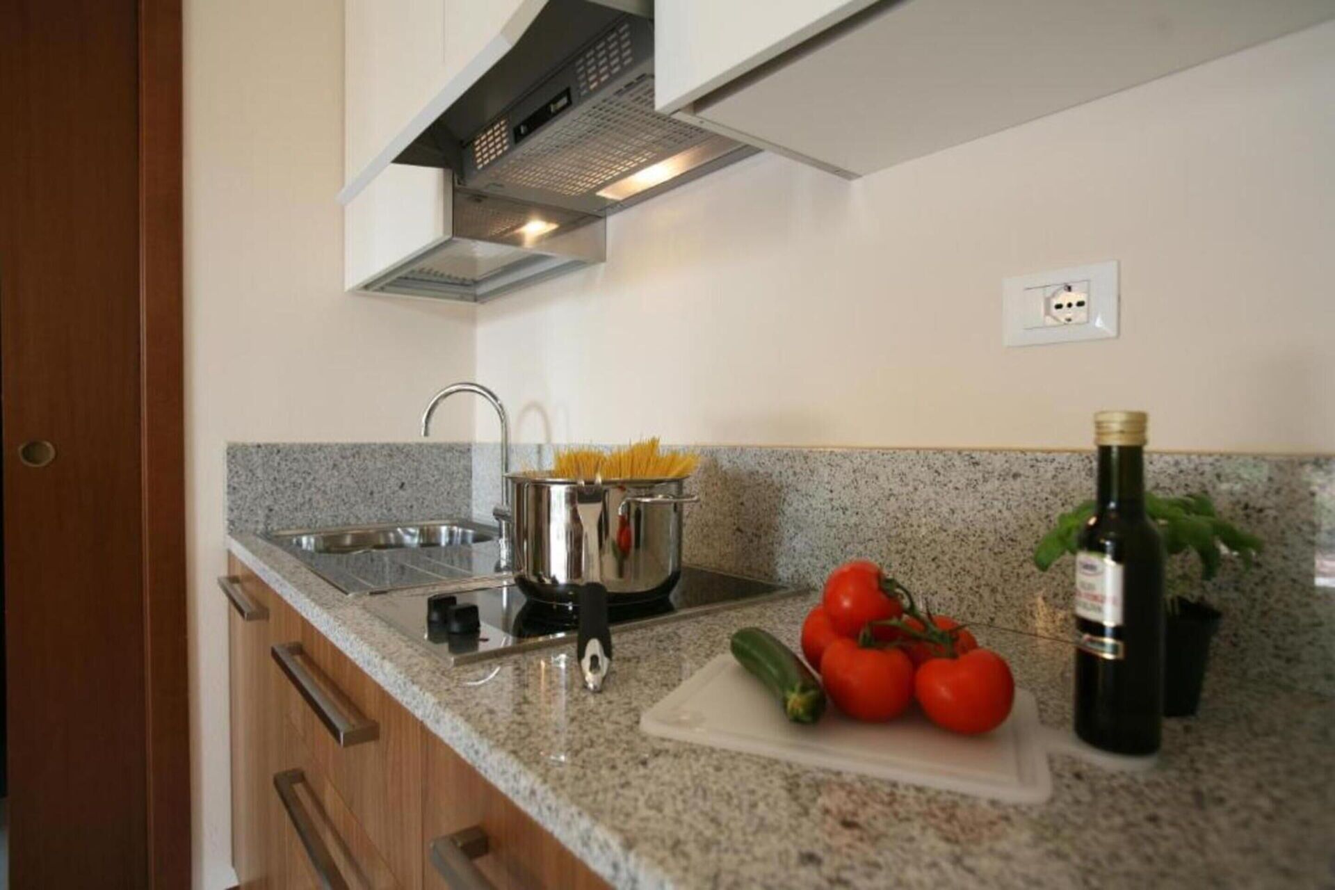 A kitchen with granite countertops, stainless steel appliances, and a potted plant.