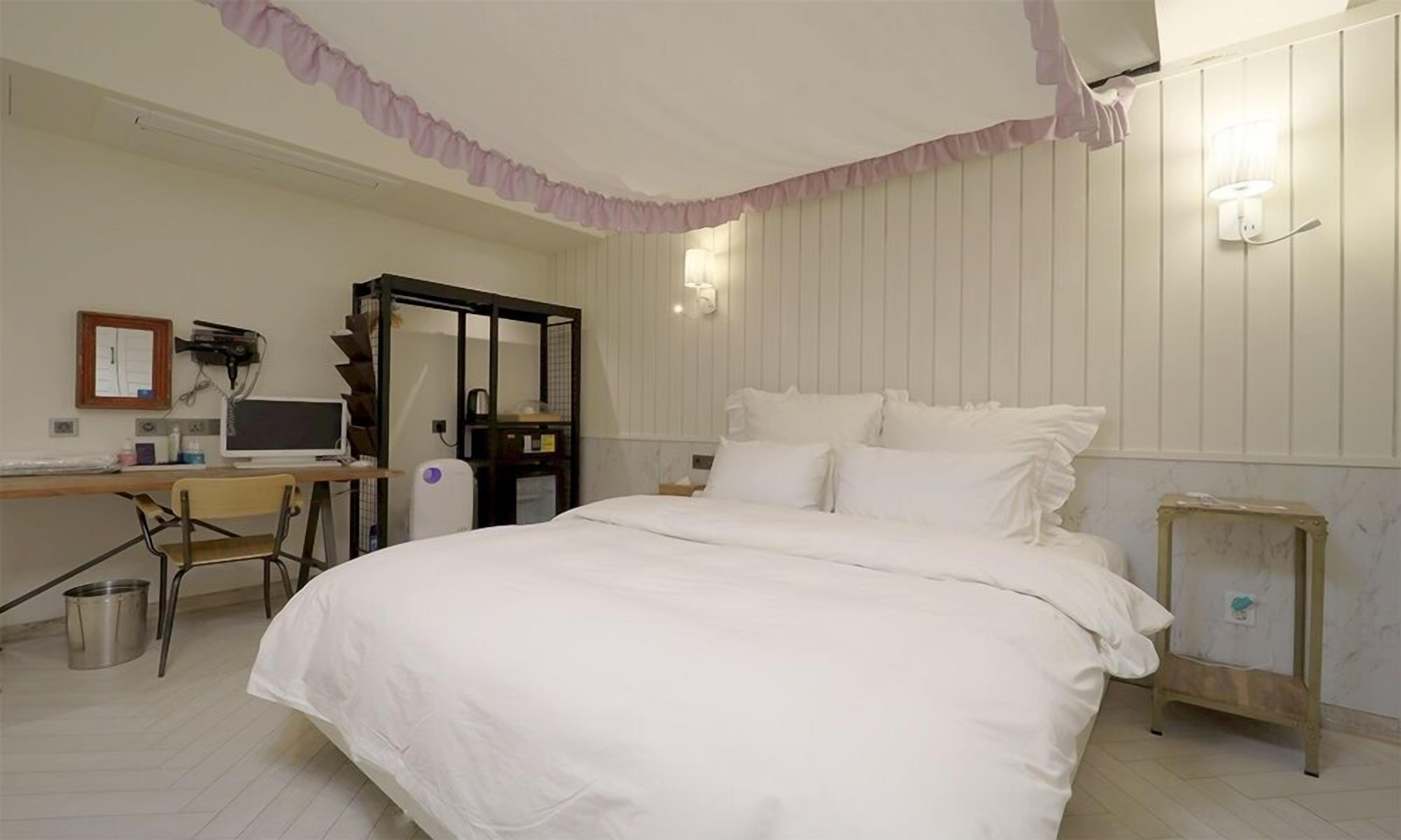 Un dormitorio con cama, escritorio y silla.
