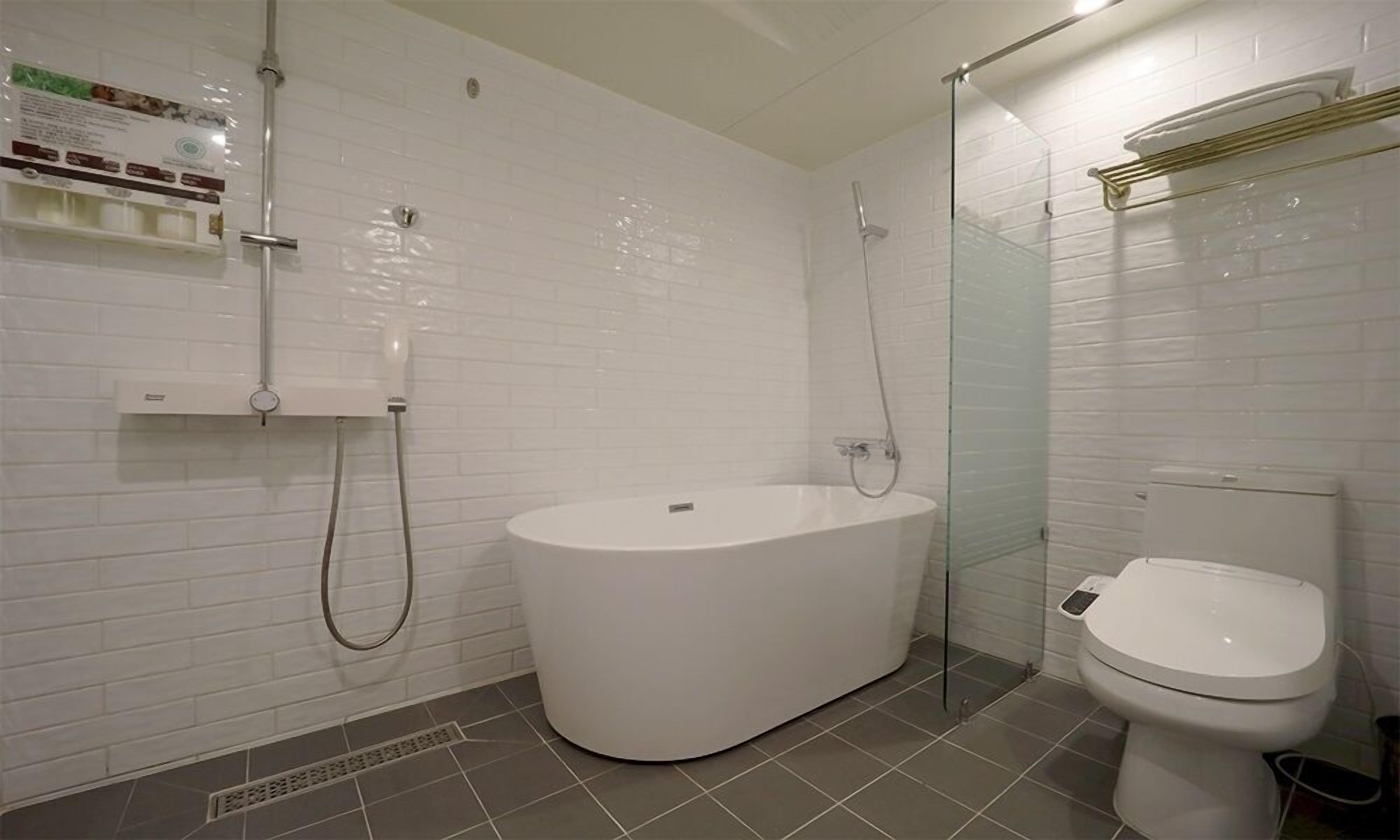 A modern bathroom with a freestanding bathtub, a glass-enclosed shower, and a toilet.