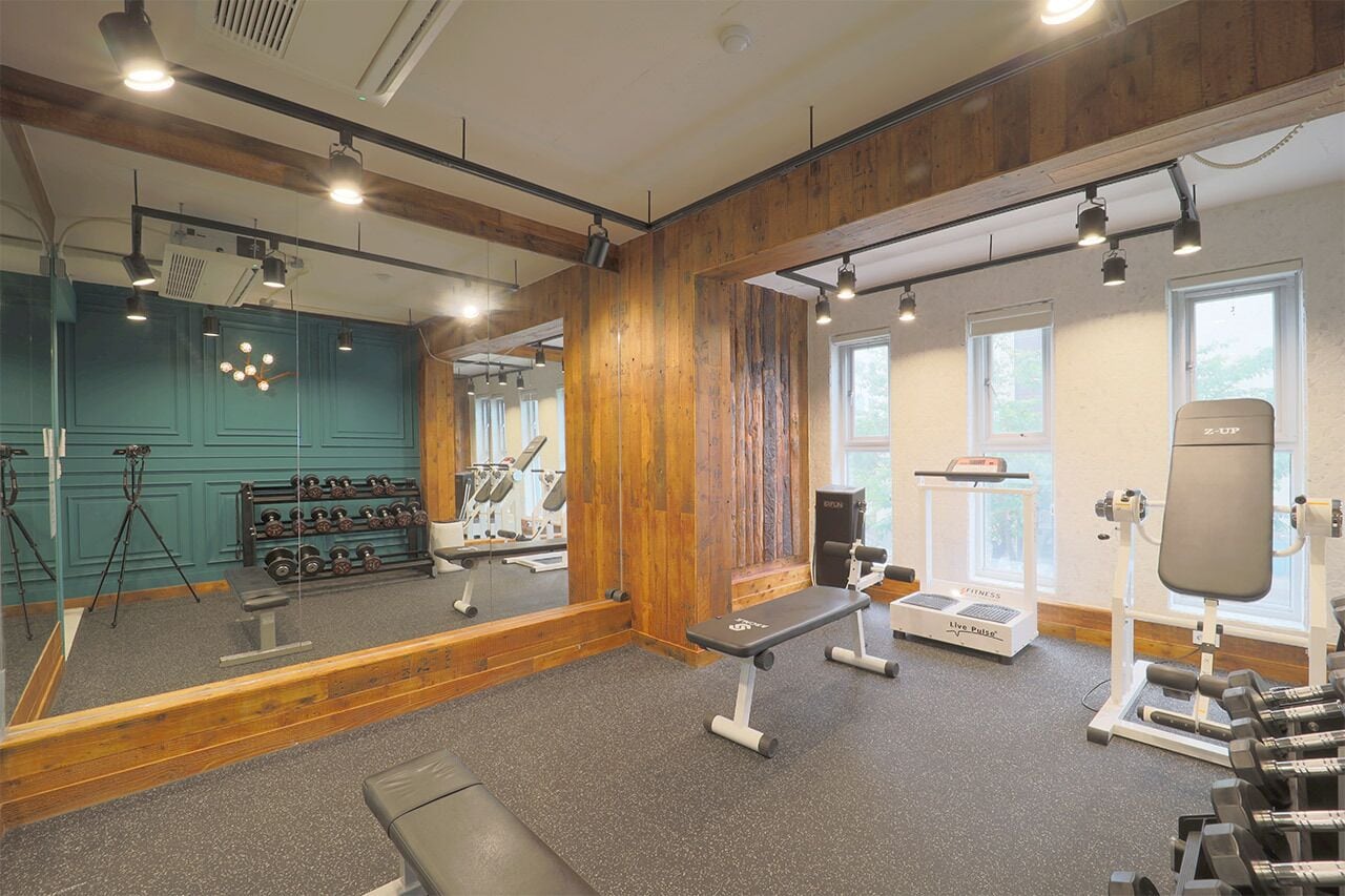 Un gimnasio con equipo de ejercicio, una banca y un muro con espejos.
