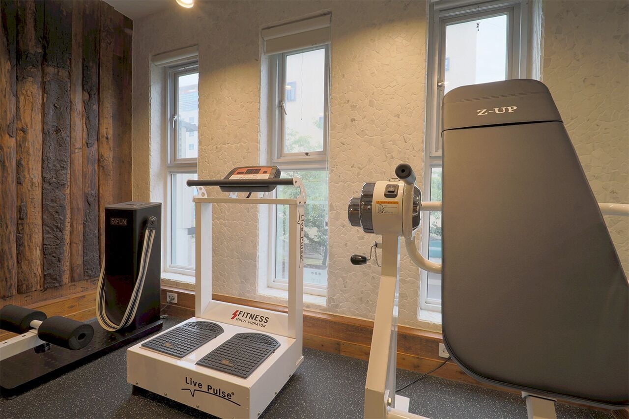 A fitness room with exercise equipment, a window, and a wooden wall.