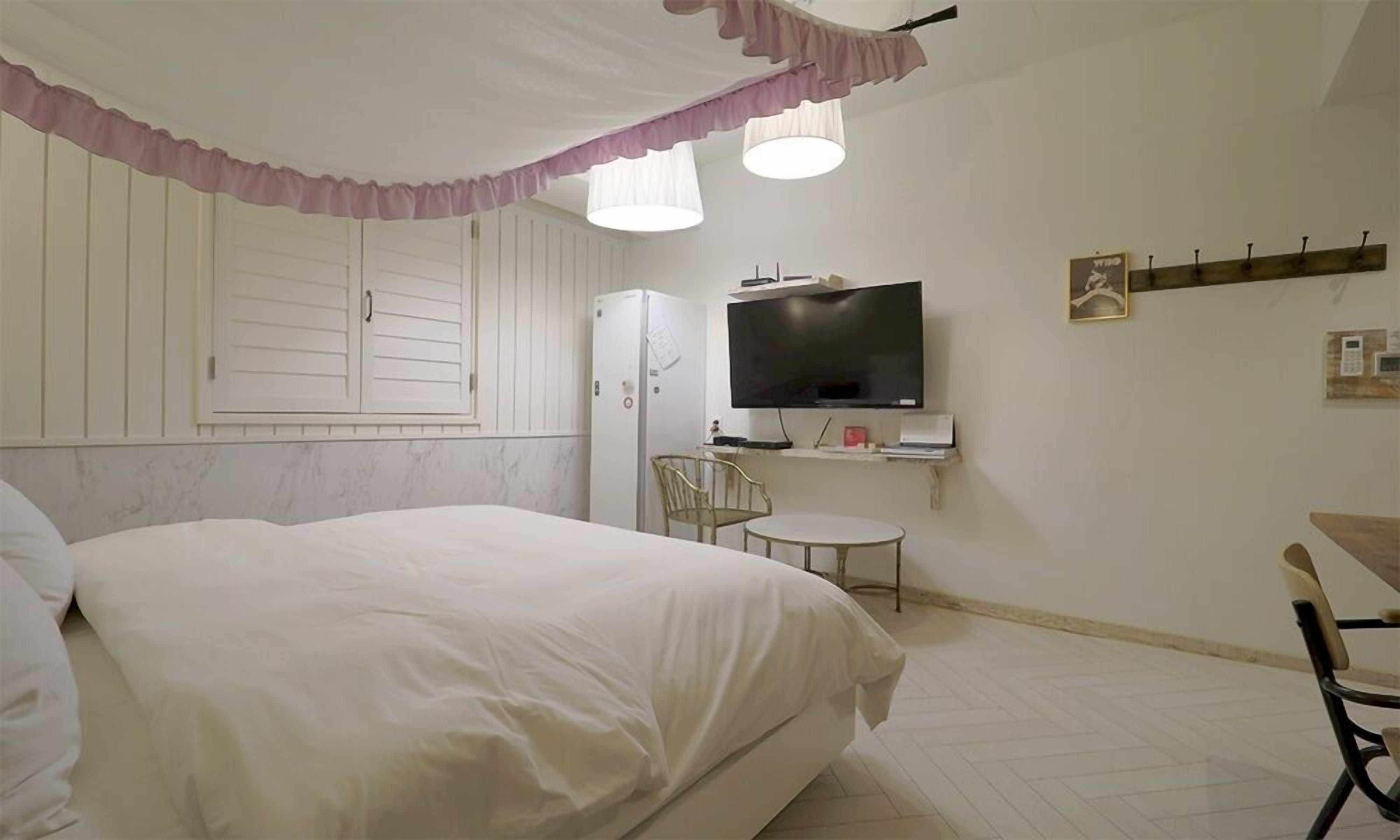 Un dormitorio con cama, televisión, una mesita y una silla.