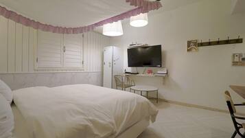Un dormitorio con cama, televisión, una mesita y una silla.